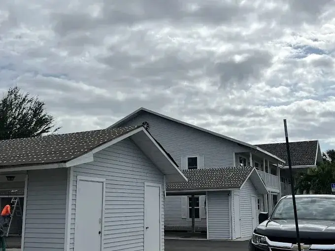 Gray cottage-style home with a new shingle roof under a cloudy sky