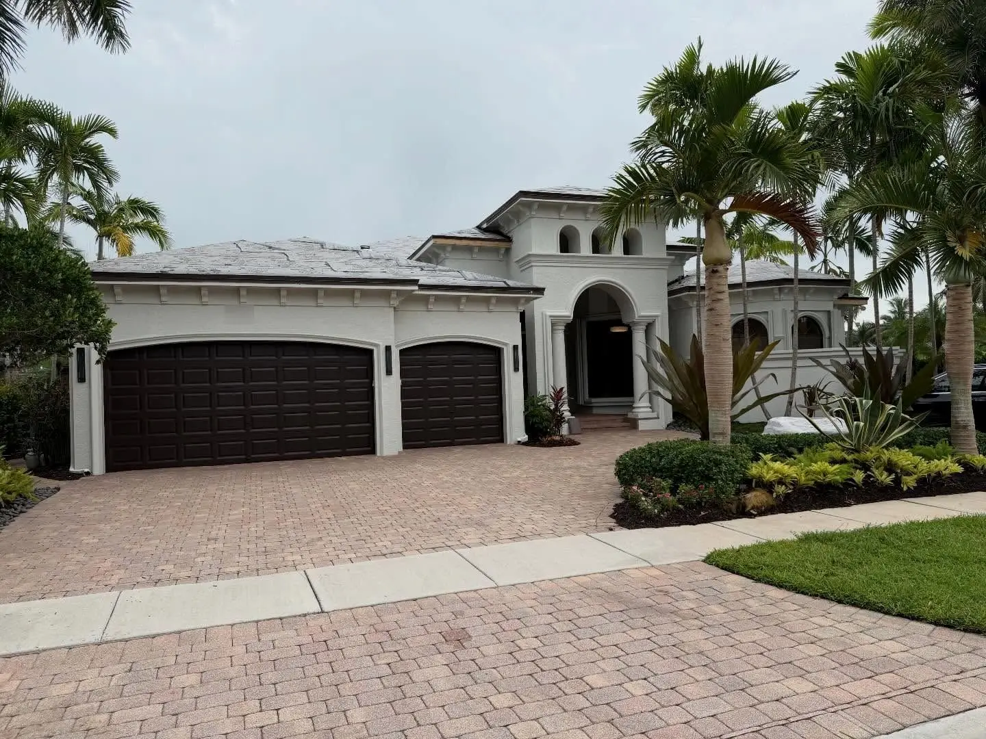 Front of a white Mediterranean home in Hawks Landing, Plantation, with dark garage doors and a roof dried in for tile