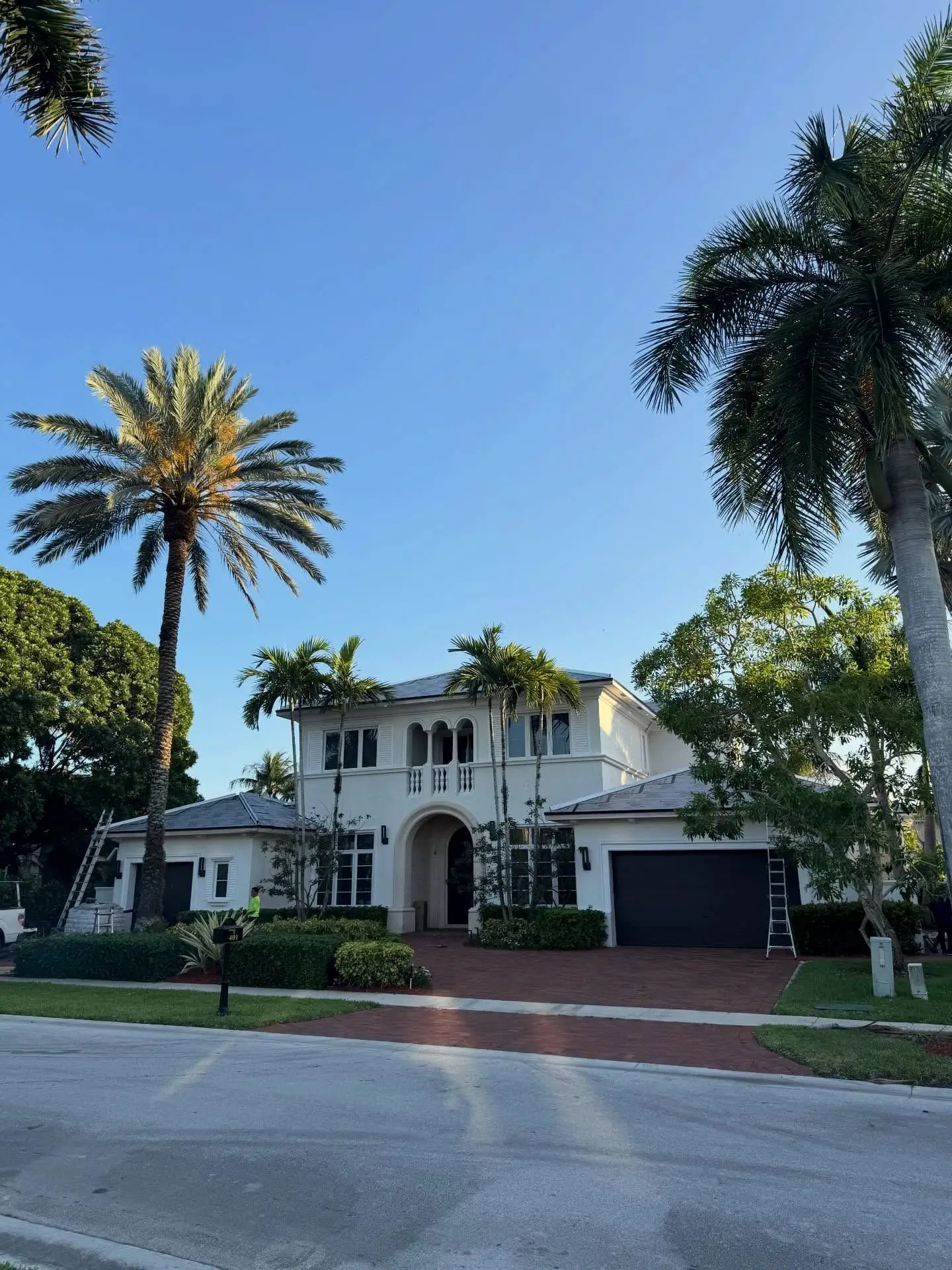 Two-story white home in Hawks Landing, Plantation, at golden hour beneath tall palms, its roof prepared for new tile