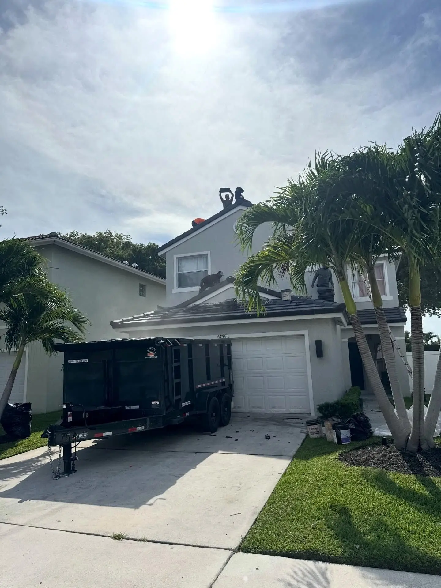 Two-story home in Lake Worth with a nearly finished Westlake Royal Saxony 900 concrete tile roof and a dumpster in the driveway