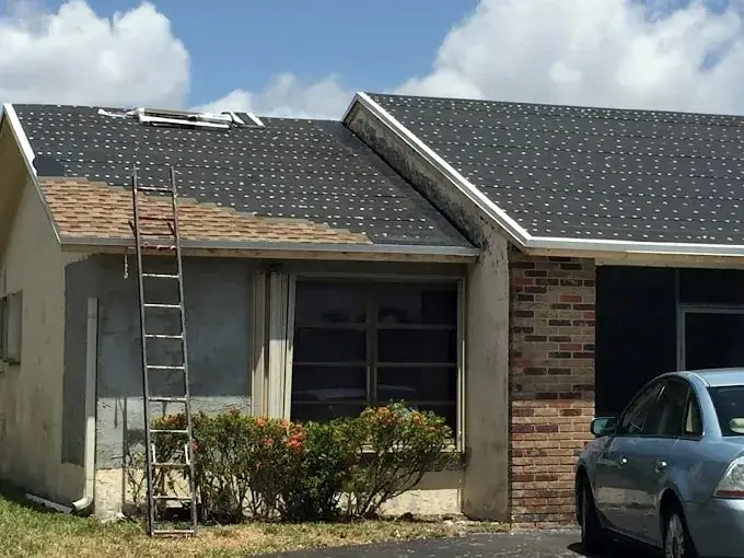 Shingle re-roof underway, with new underlayment and shingles meeting the old roof