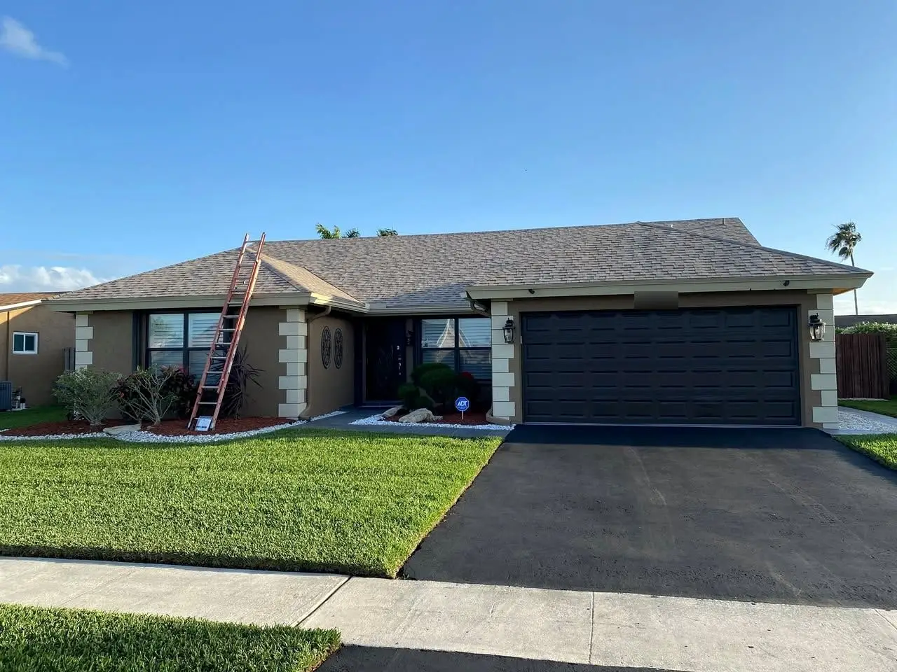 Single-story home with a newly finished gray shingle roof and a freshly sealed driveway