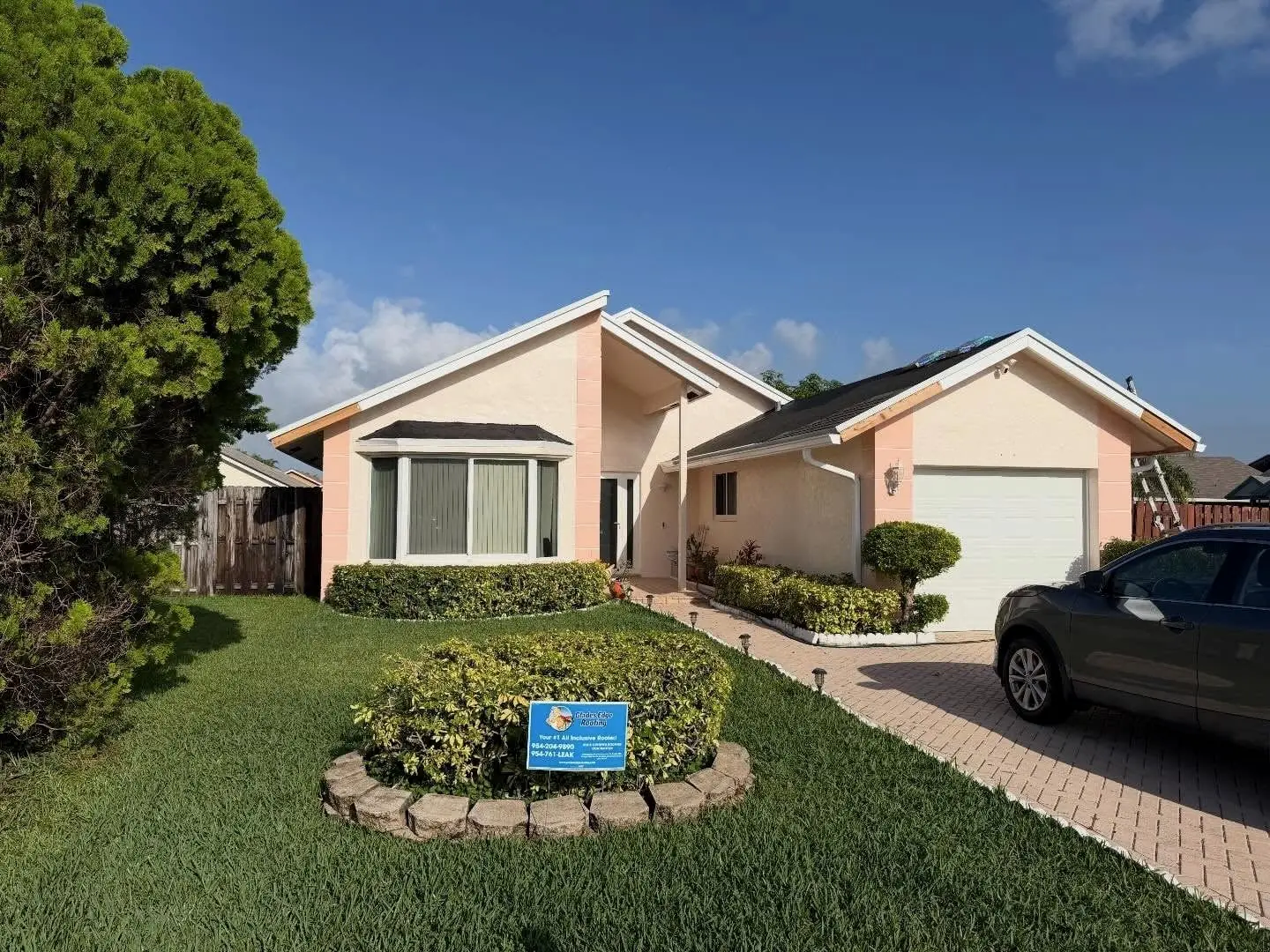 Peach stucco home in Sunrise with its roof dried in and ready for shingles, a Glades Edge Roofing sign on the lawn