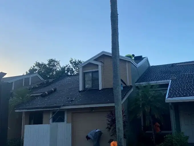 Two-story townhome with a new dark shingle roof as the crew finishes up
